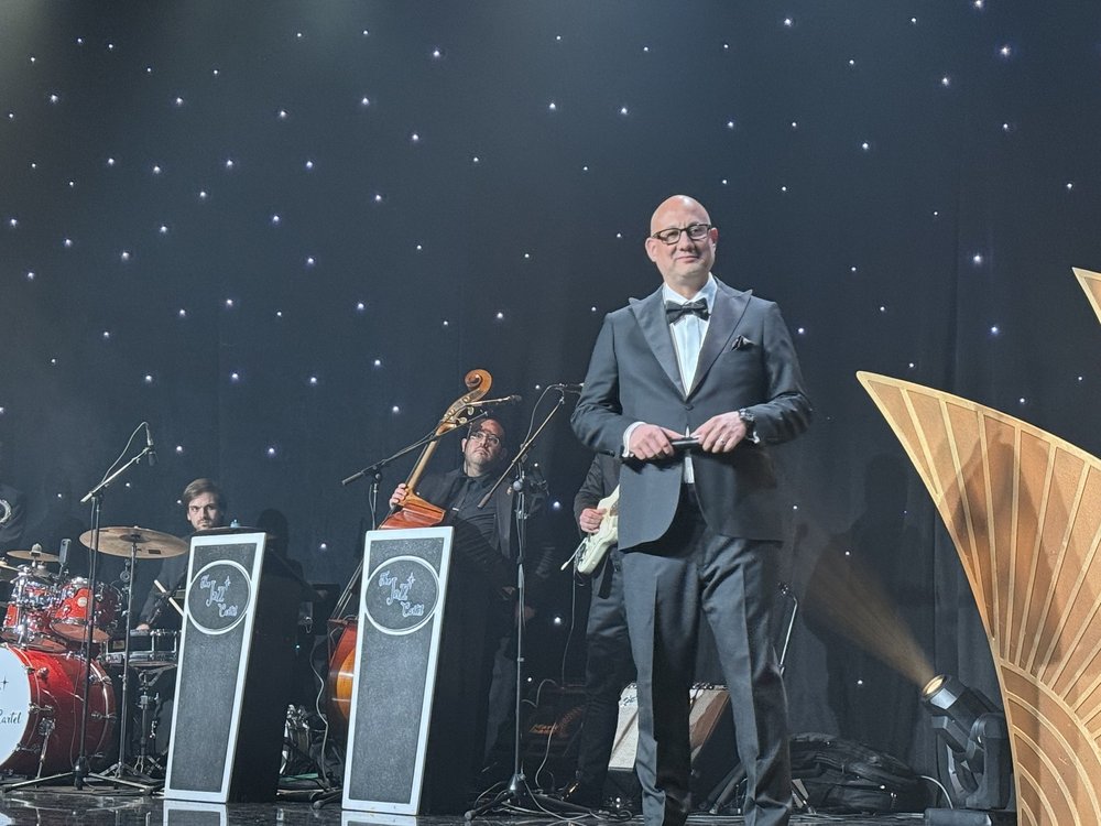 Luis Giraldo performs on stage at the Beverly Hilton with a jazz trio and art deco backdrop